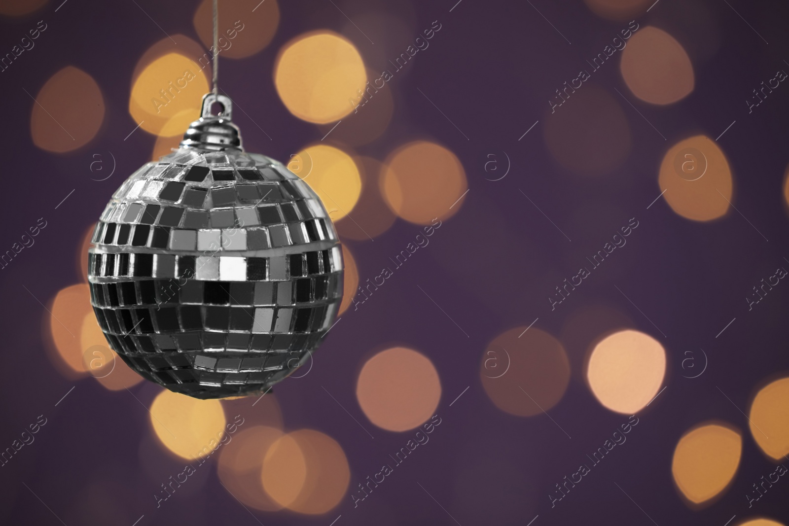 Photo of Shiny disco ball against blurred lights, space for text