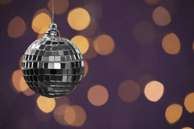 Shiny disco ball against blurred lights, space for text