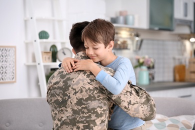 Young man in military uniform with his little son at home