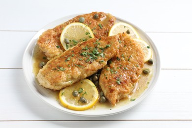 Photo of Delicious chicken piccata on white wooden table