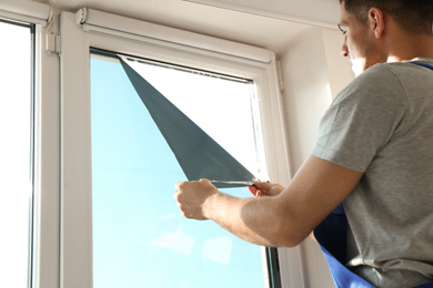 Photo of Professional worker tinting window with foil indoors