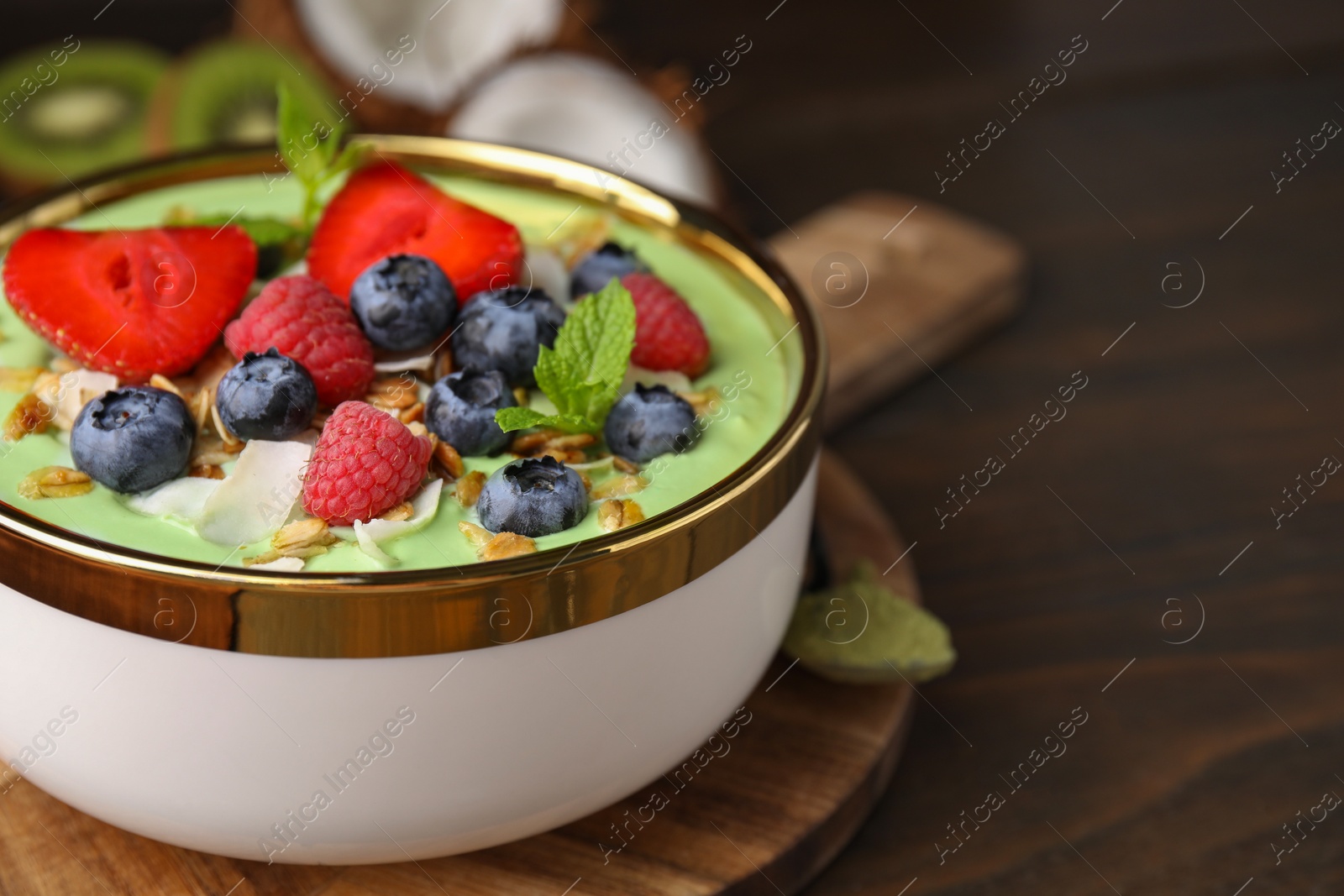 Photo of Tasty matcha smoothie bowl served with berries and oatmeal on wooden table, closeup with space for text. Healthy breakfast