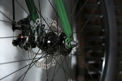 Photo of Modern green bicycle near grey wall indoors, closeup
