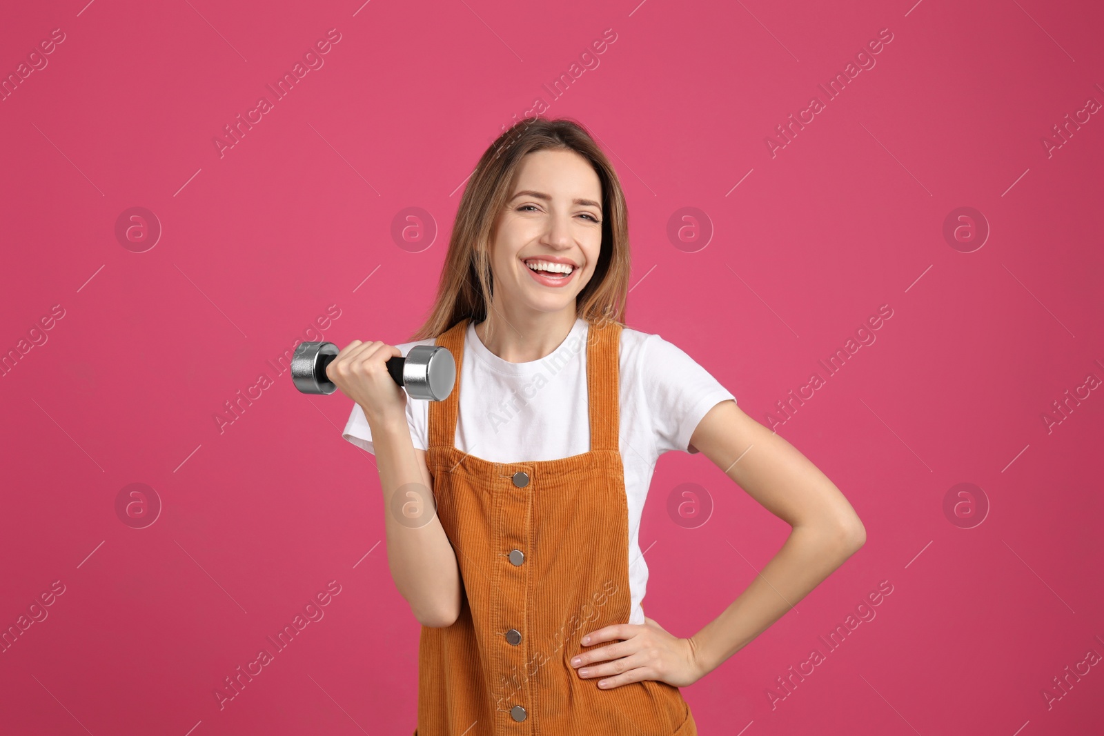 Photo of Woman with dumbbell as symbol of girl power on pink background. 8 March concept