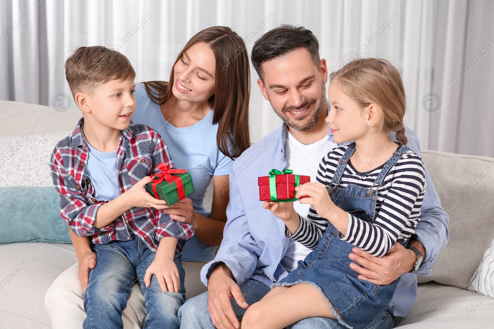 Photo of Happy family presenting each other with gifts on sofa at home