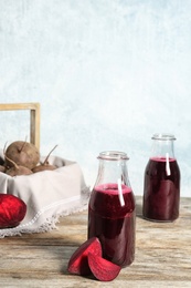 Bottle of beet smoothie on wooden table, space for text