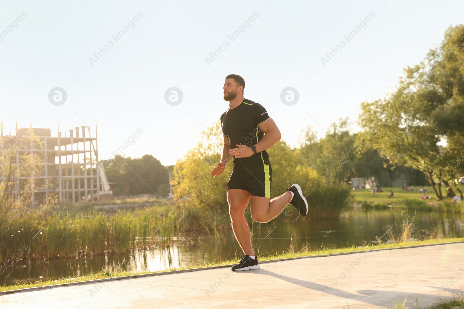 Photo of Young man running near pond in park