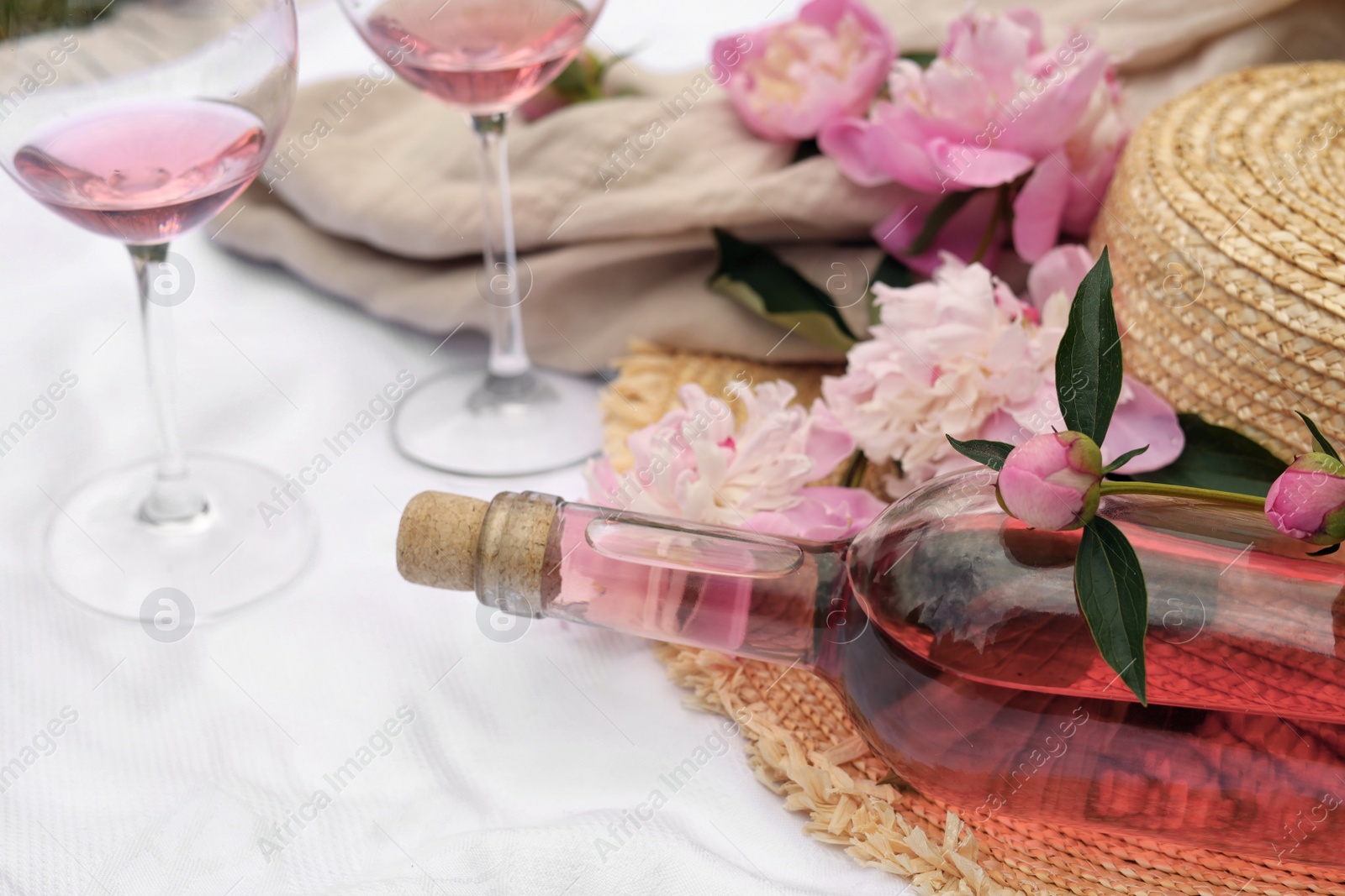 Photo of Bottle of rose wine and peonies on white fabric
