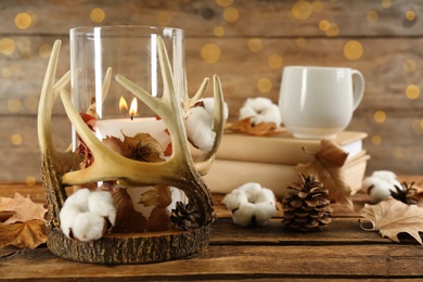 Photo of Stylish holder with burning candle and autumn decor on wooden table. Space for text