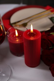 Photo of Place setting with red candles on white table, closeup. Romantic dinner