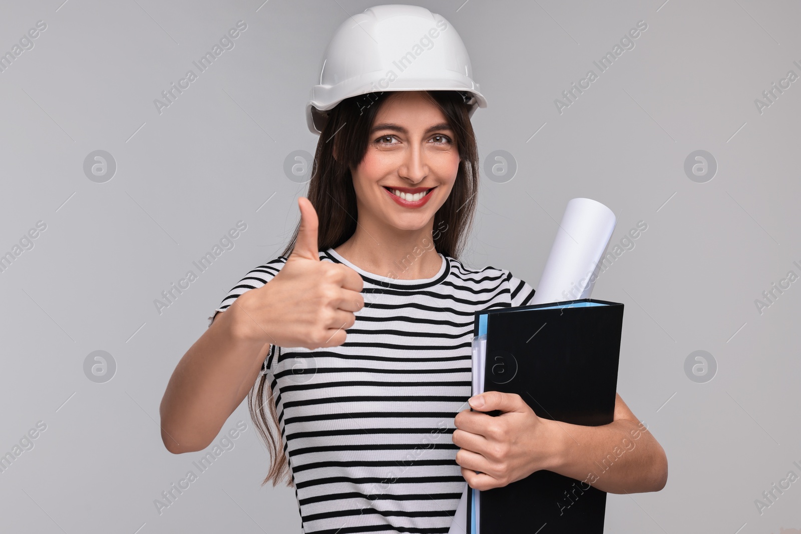 Photo of Architect in hard hat with draft and folder showing thumbs up on light grey background