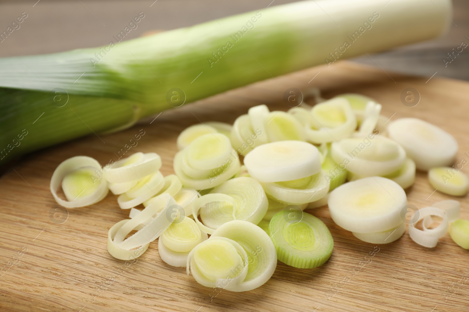 Photo of Fresh raw leek slices on wooden table, closeup