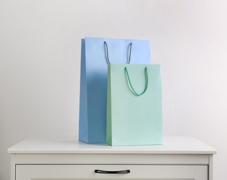 Paper shopping bags on white chest of drawers against light background