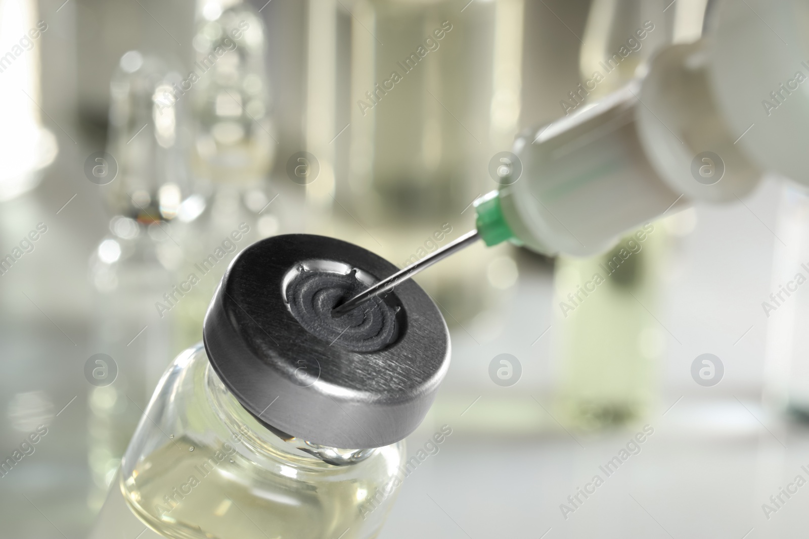 Photo of Filling syringe with medicine from vial against blurred background, closeup