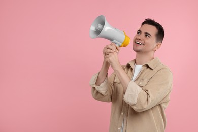 Special promotion. Young man shouting in megaphone on pink background, space for text