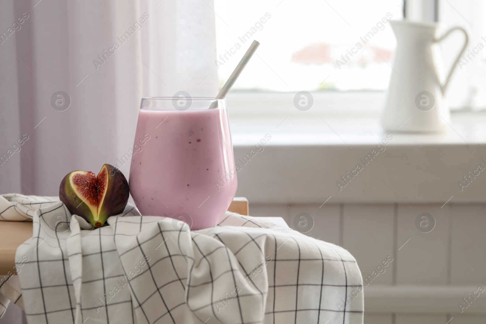 Photo of Delicious fig smoothie in glass on table indoors