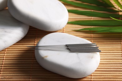 Stones with acupuncture needles on bamboo mat