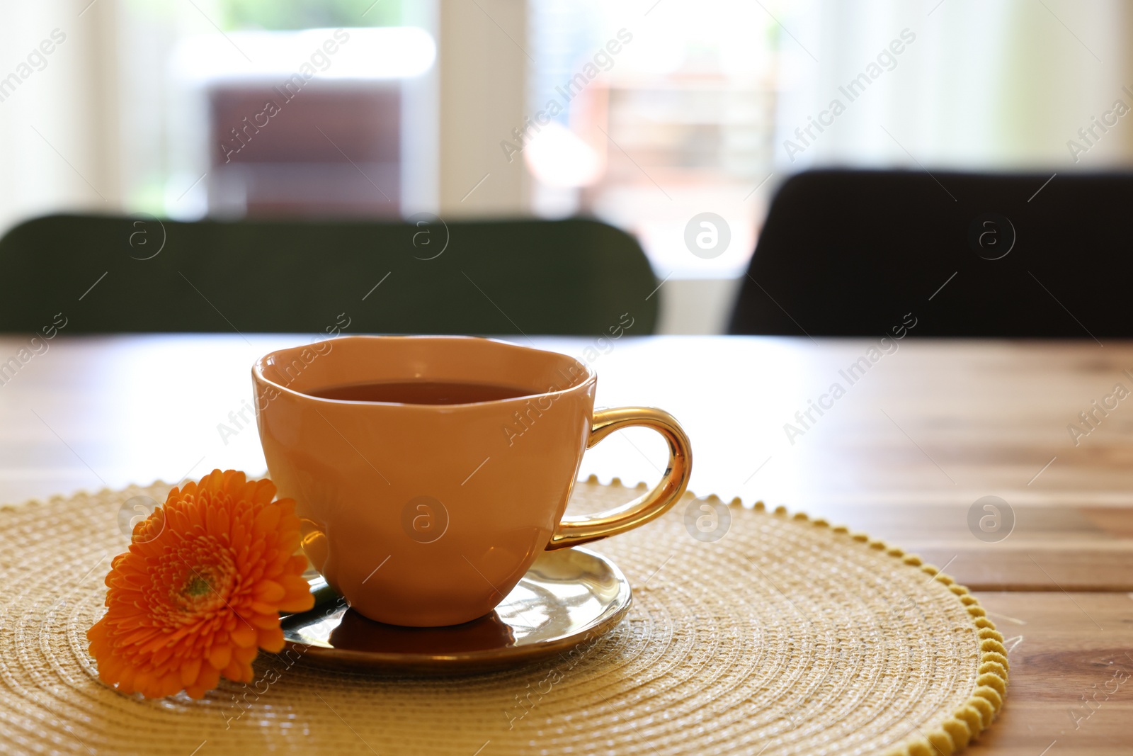 Photo of Cup of delicious chamomile tea and fresh calendula flower on wooden table in room, space for text