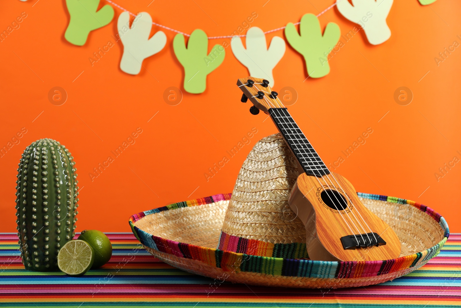 Photo of Composition with Mexican sombrero hat and ukulele on color table, closeup