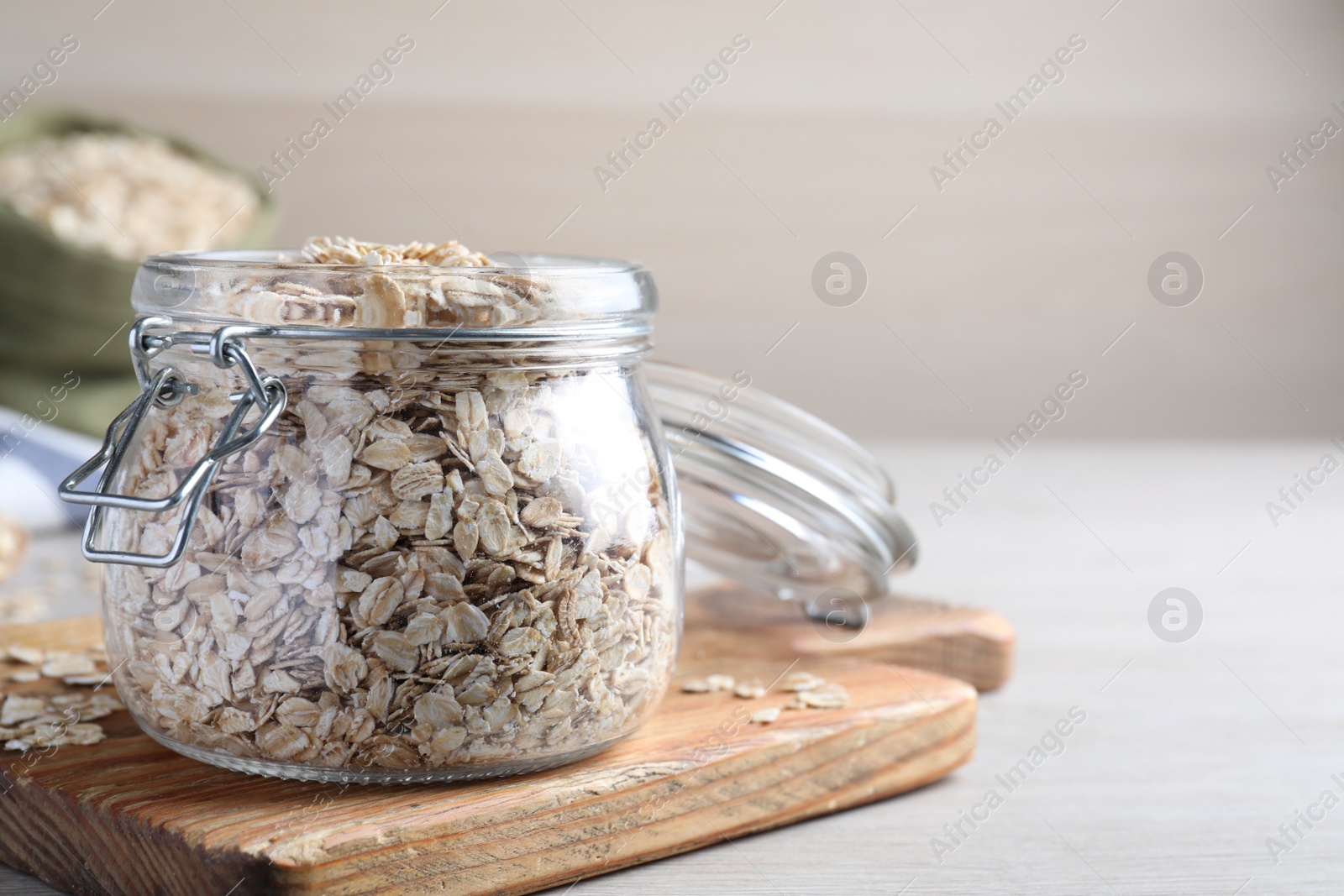 Photo of Glass jar with oatmeal on white wooden table. Space for text