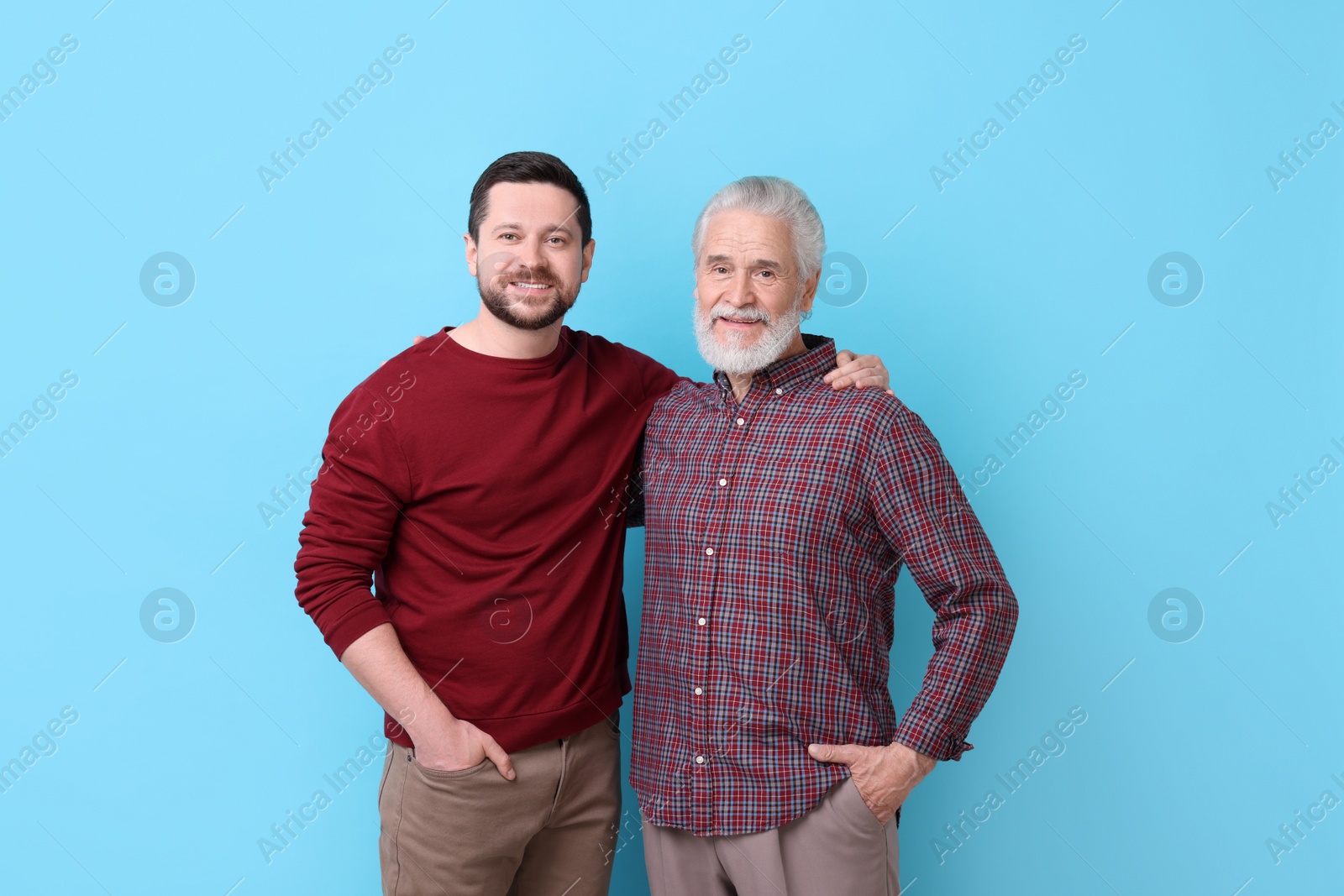 Photo of Happy son and his dad on light blue background