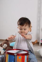 Photo of Cute little boy playing toy drum at home