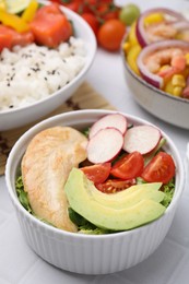 Photo of Delicious poke bowl with meat, avocado and vegetables on white table