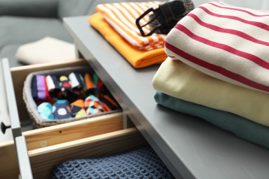 Photo of Chest of drawers with different folded clothes indoors, closeup