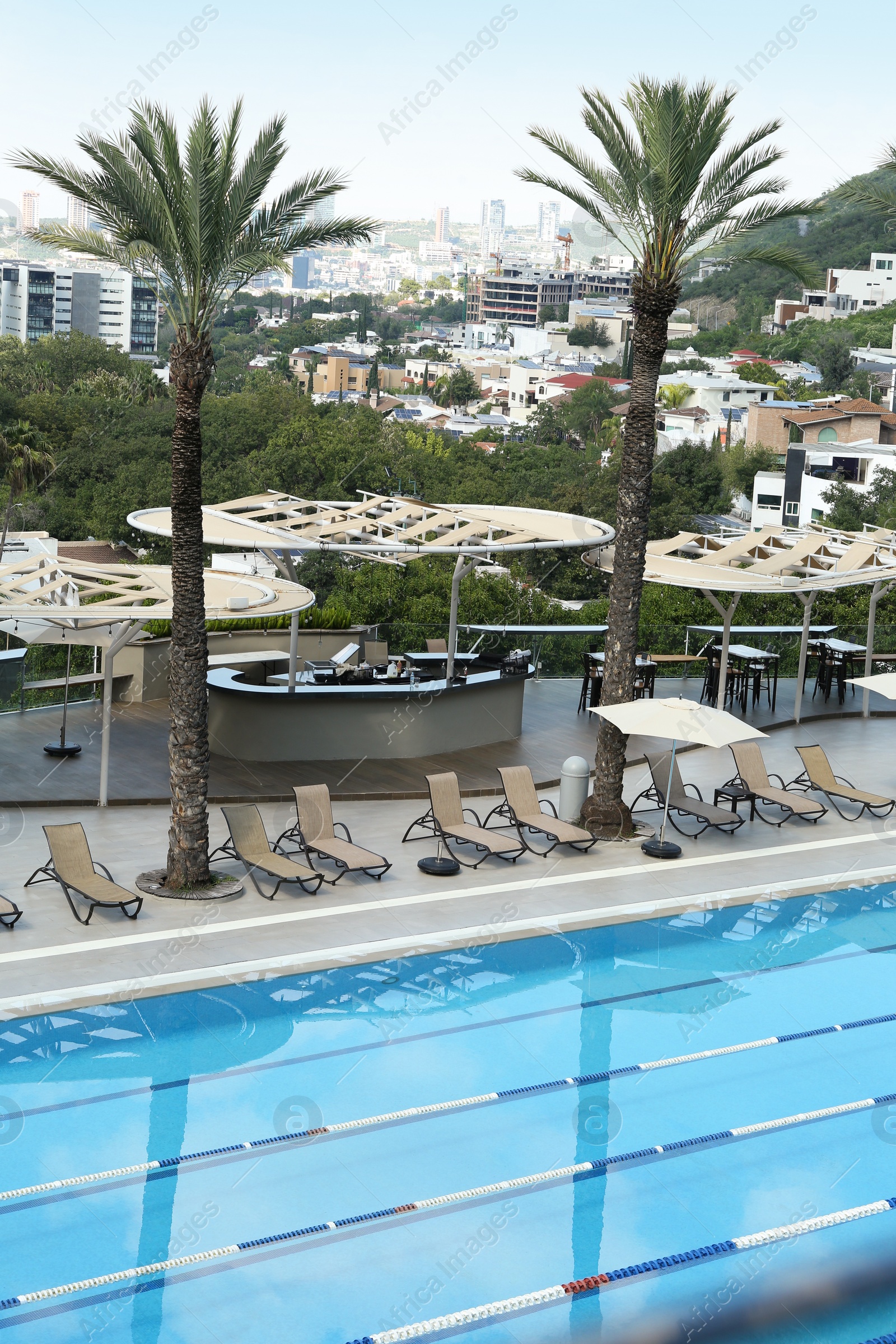 Photo of Outdoor swimming pool and tropical plants at luxury resort on sunny day