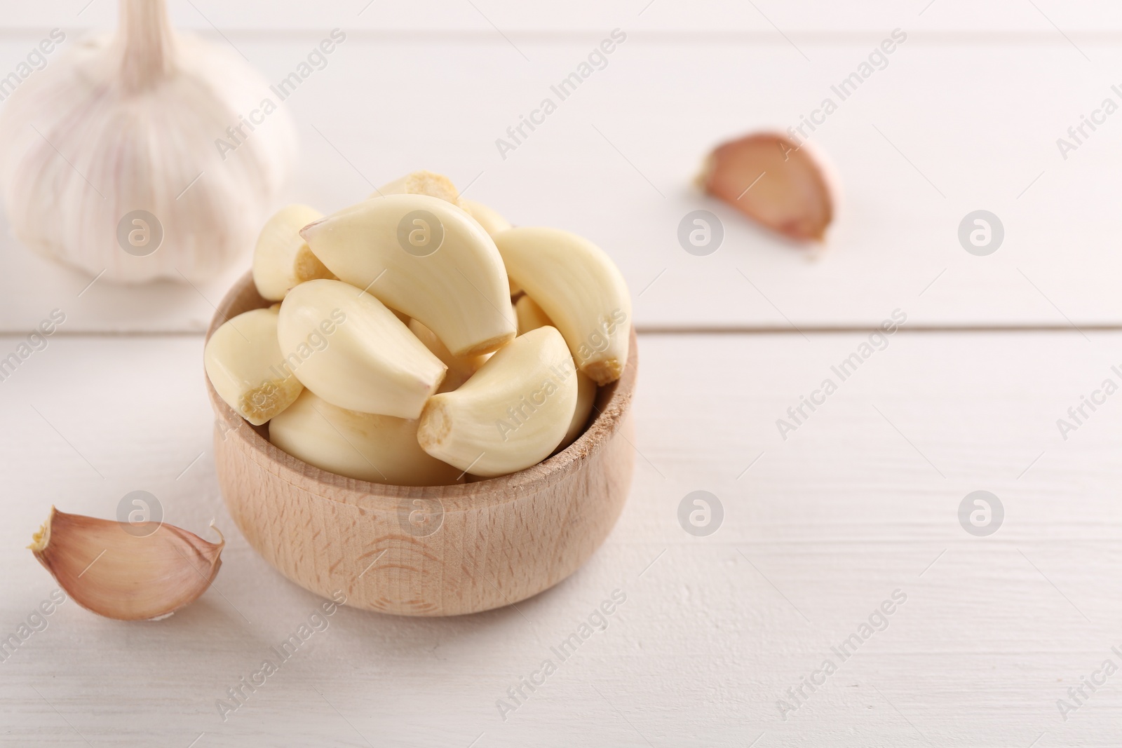 Photo of Fresh garlic on white wooden table, closeup. Space for text