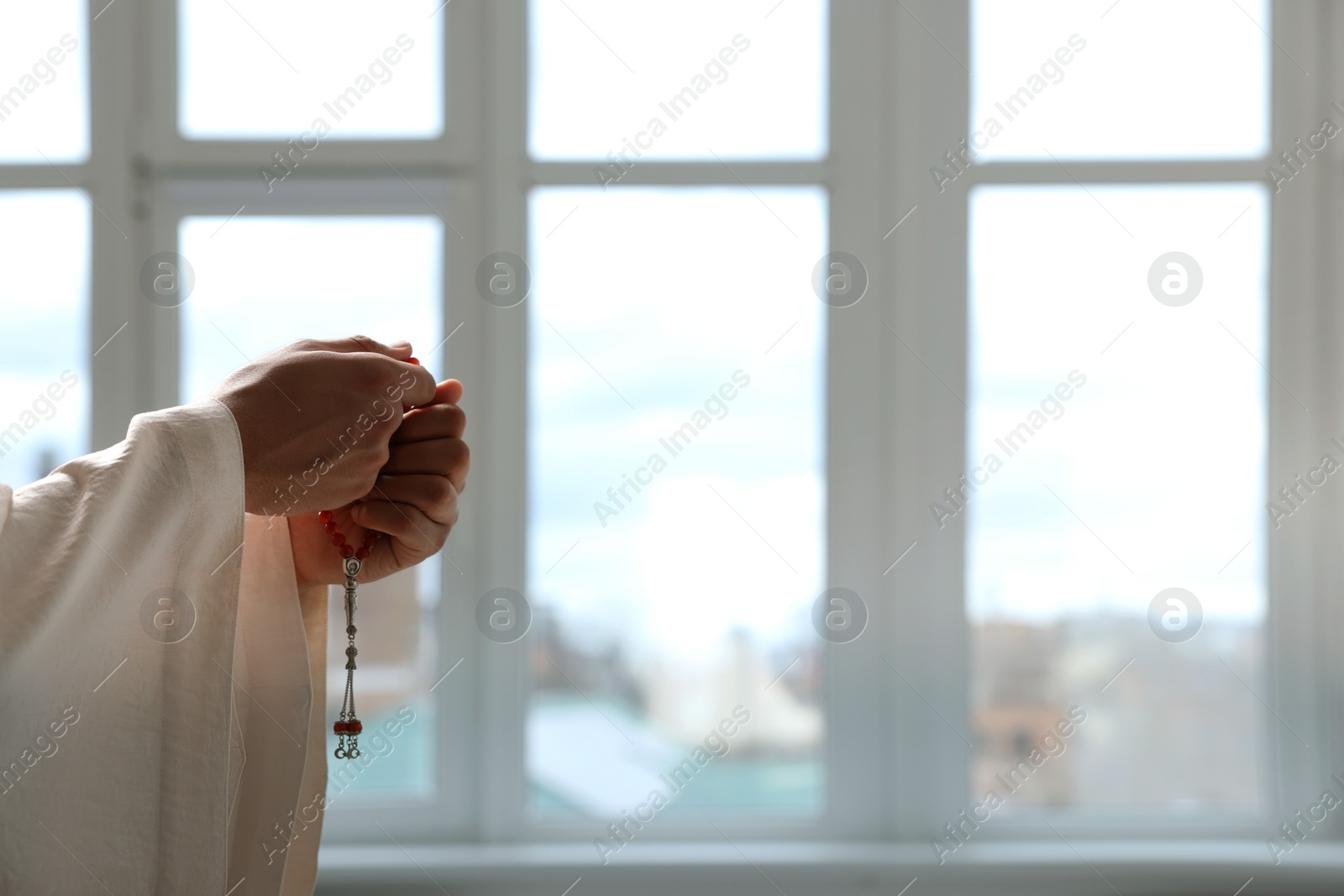 Photo of Muslim man with misbaha praying indoors, closeup. Space for text