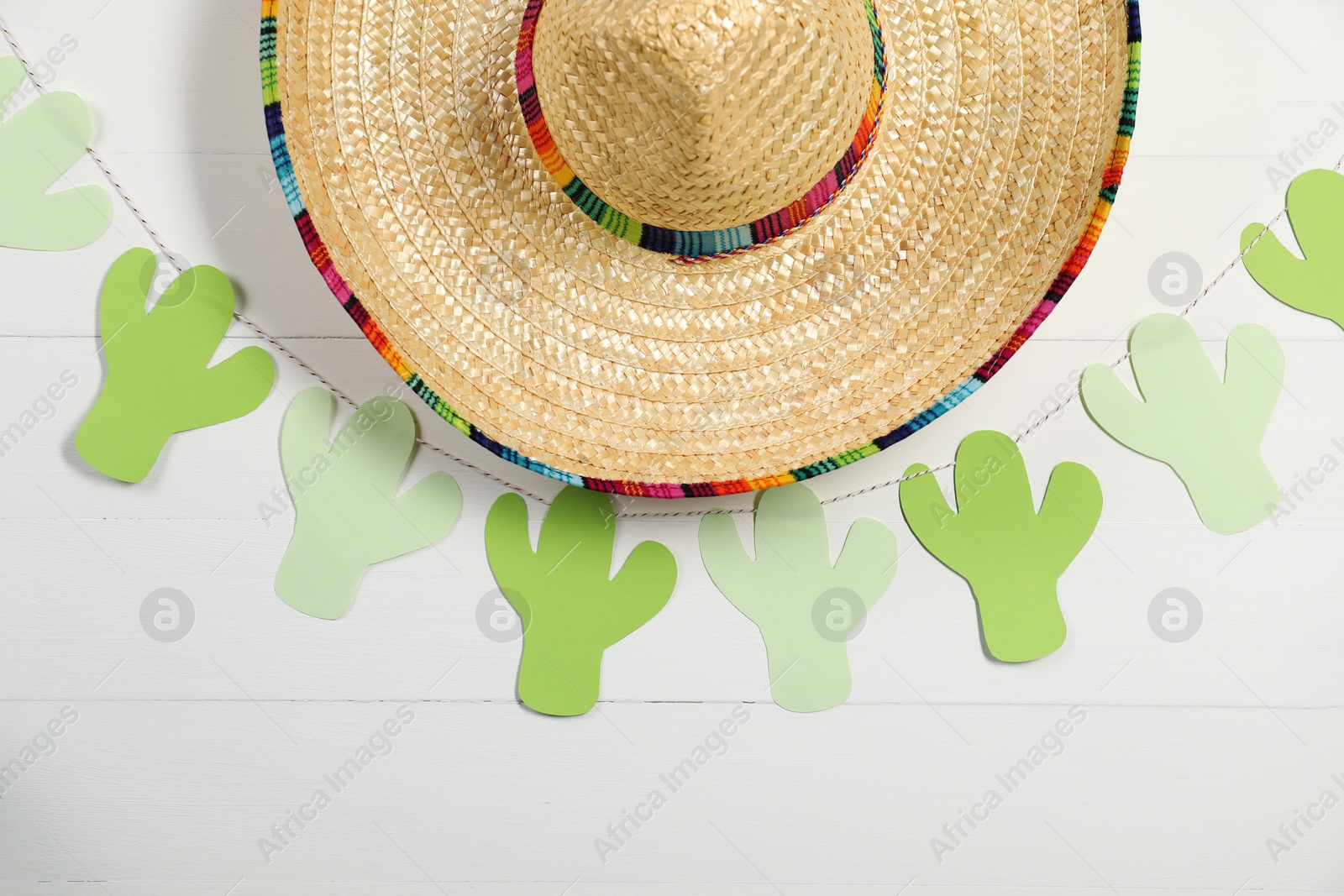 Photo of Mexican sombrero hat and garland on white wooden background