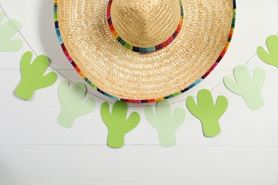 Photo of Mexican sombrero hat and garland on white wooden background