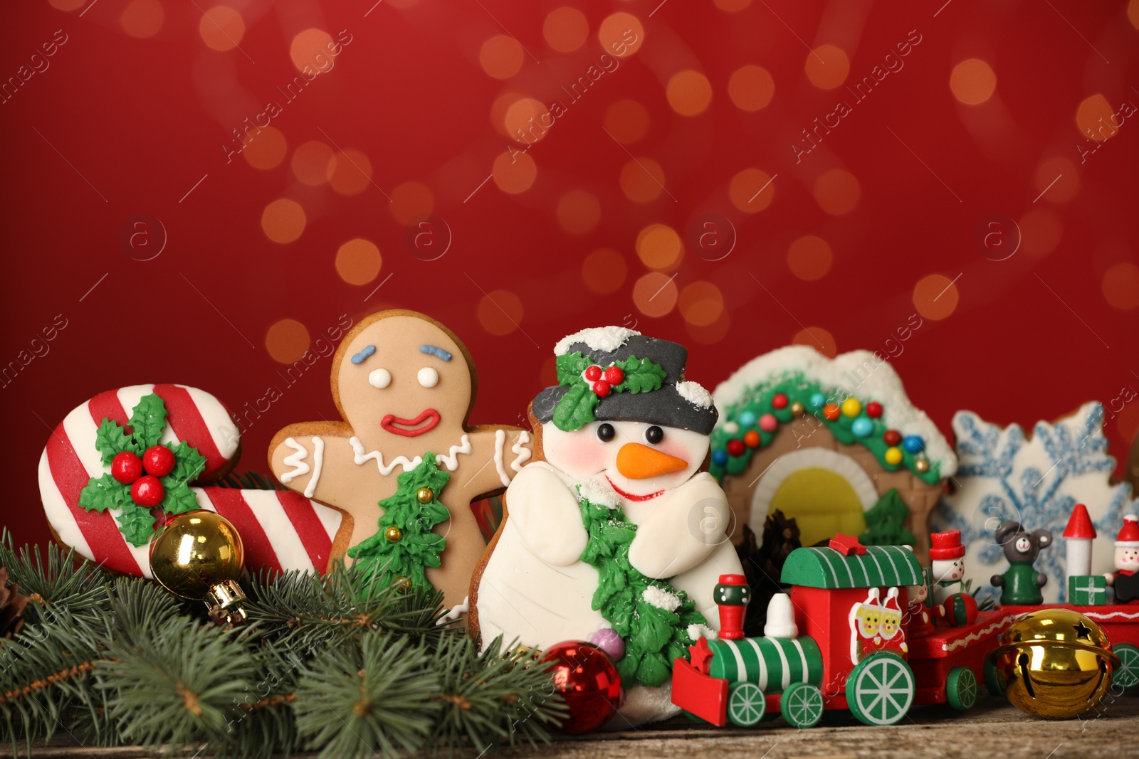 Photo of Sweet Christmas cookies and decor on wooden table against blurred festive lights. Space for text