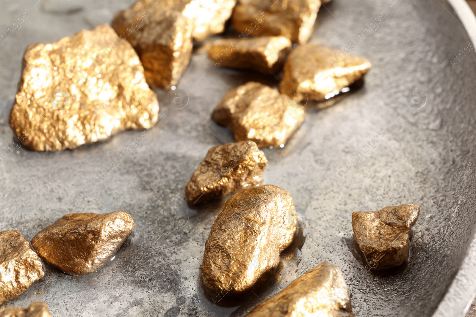 Photo of Plate with gold nuggets and water, closeup