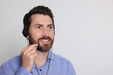 Hotline operator with headset on light grey background, space for text