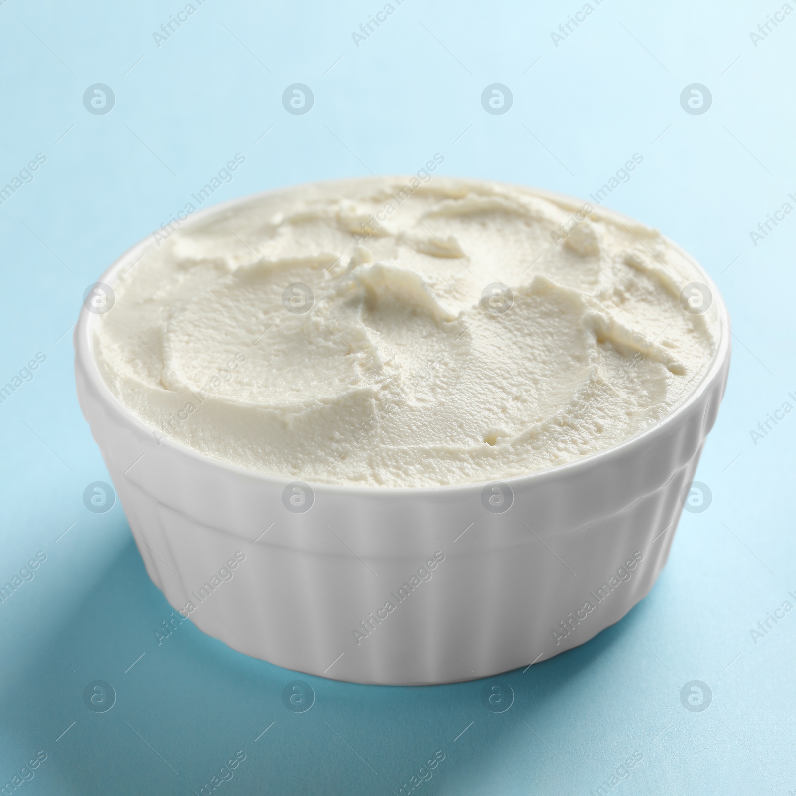 Photo of Bowl of tasty cream cheese on color background