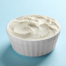 Photo of Bowl of tasty cream cheese on color background