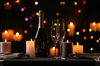 Romantic dinner table setting with burning candles and festive lights