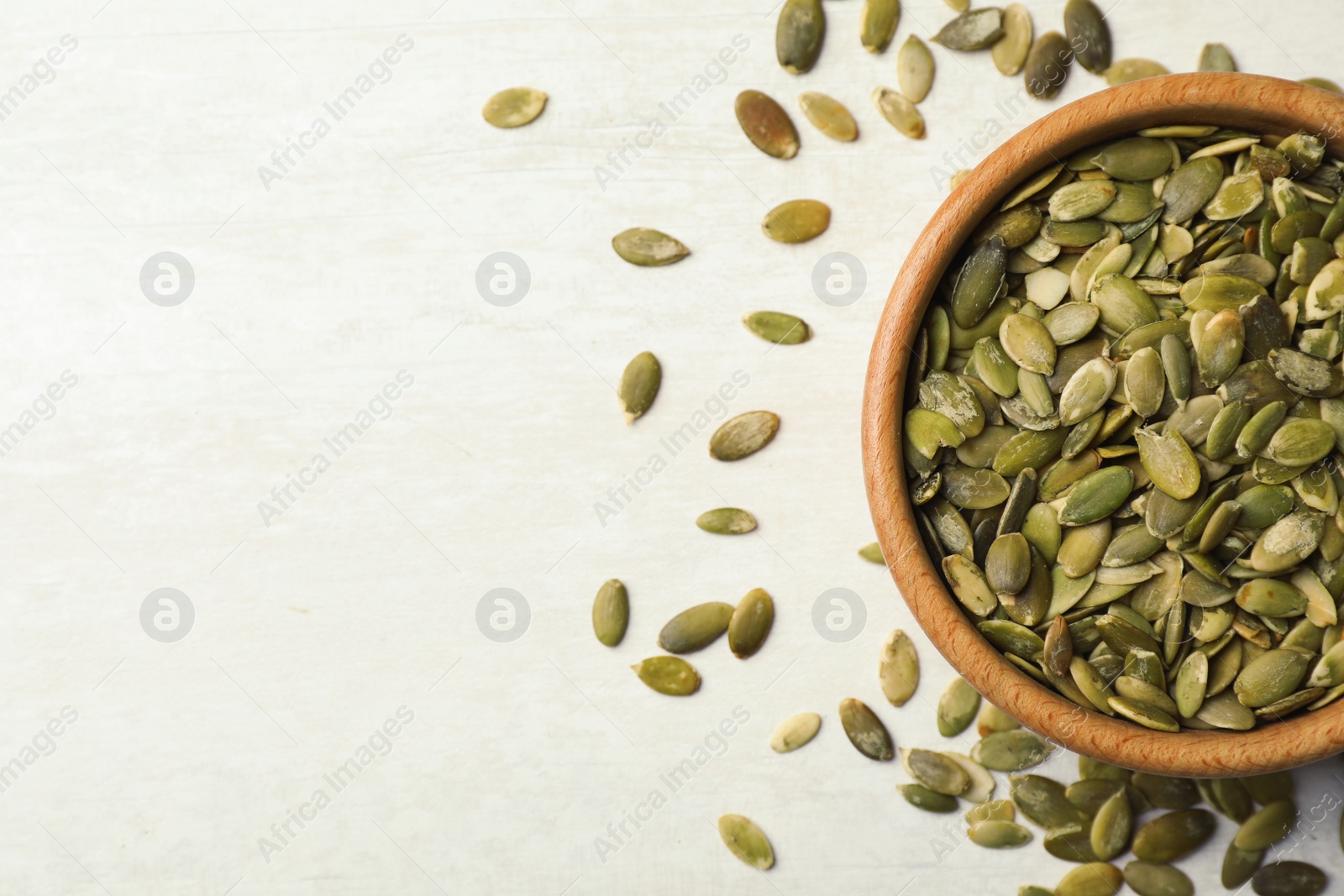 Photo of Shelled raw pumpkin seeds on light background, top view. Space for text