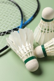 Photo of Feather badminton shuttlecocks and rackets on green background, closeup