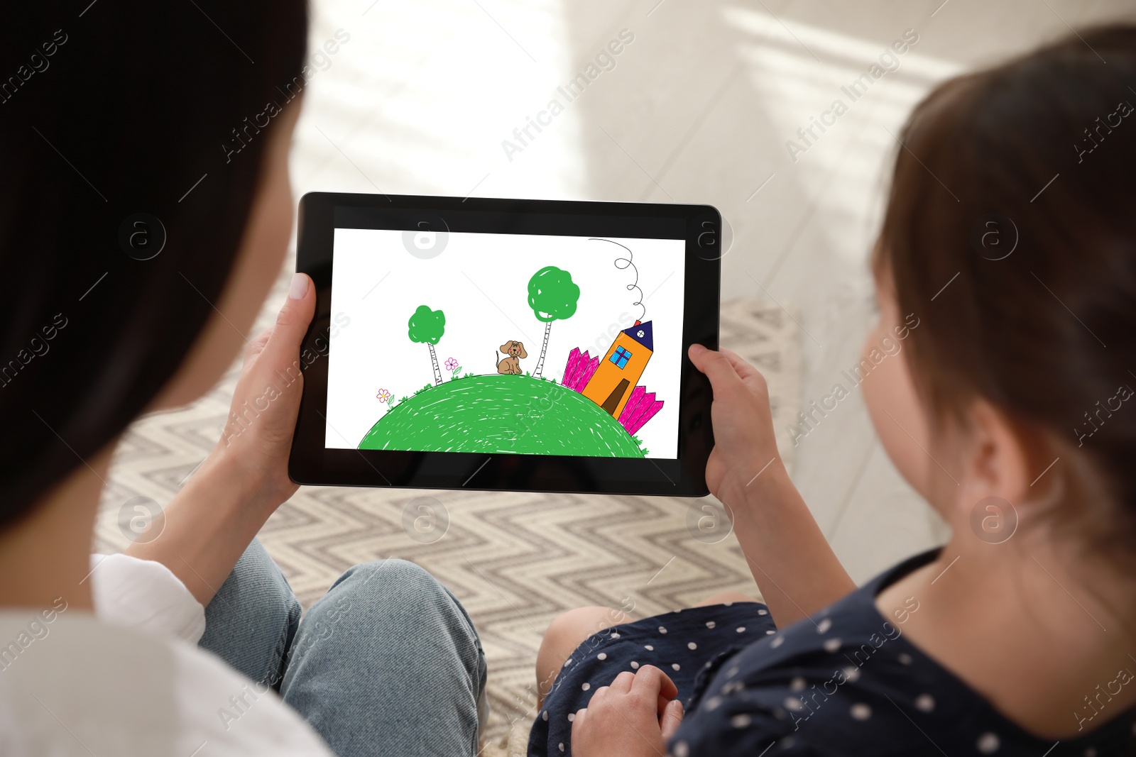 Image of Little girl showing her mother tablet with cute drawing at home. Child art