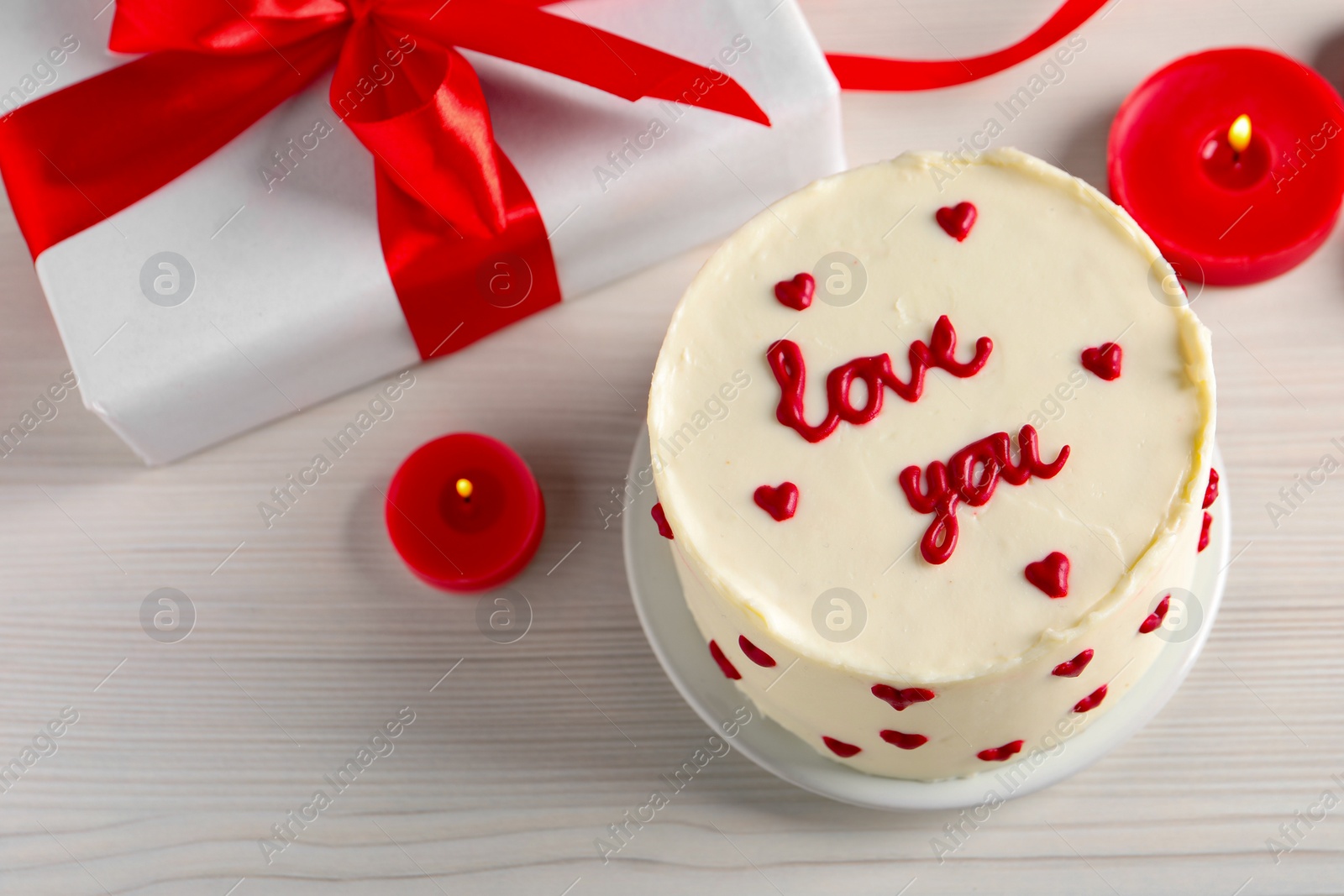 Photo of Bento cake with text Love You, candles, gift box and space for text on white wooden table, above view. St. Valentine's day surprise