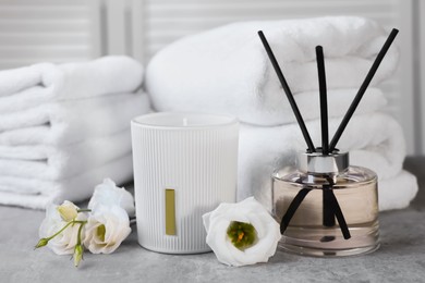 Photo of Reed diffuser, scented candle, flowers and folded towels on gray marble table