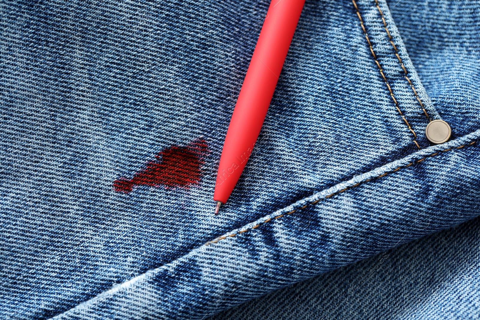 Photo of Pen and stain of red ink on jeans, top view