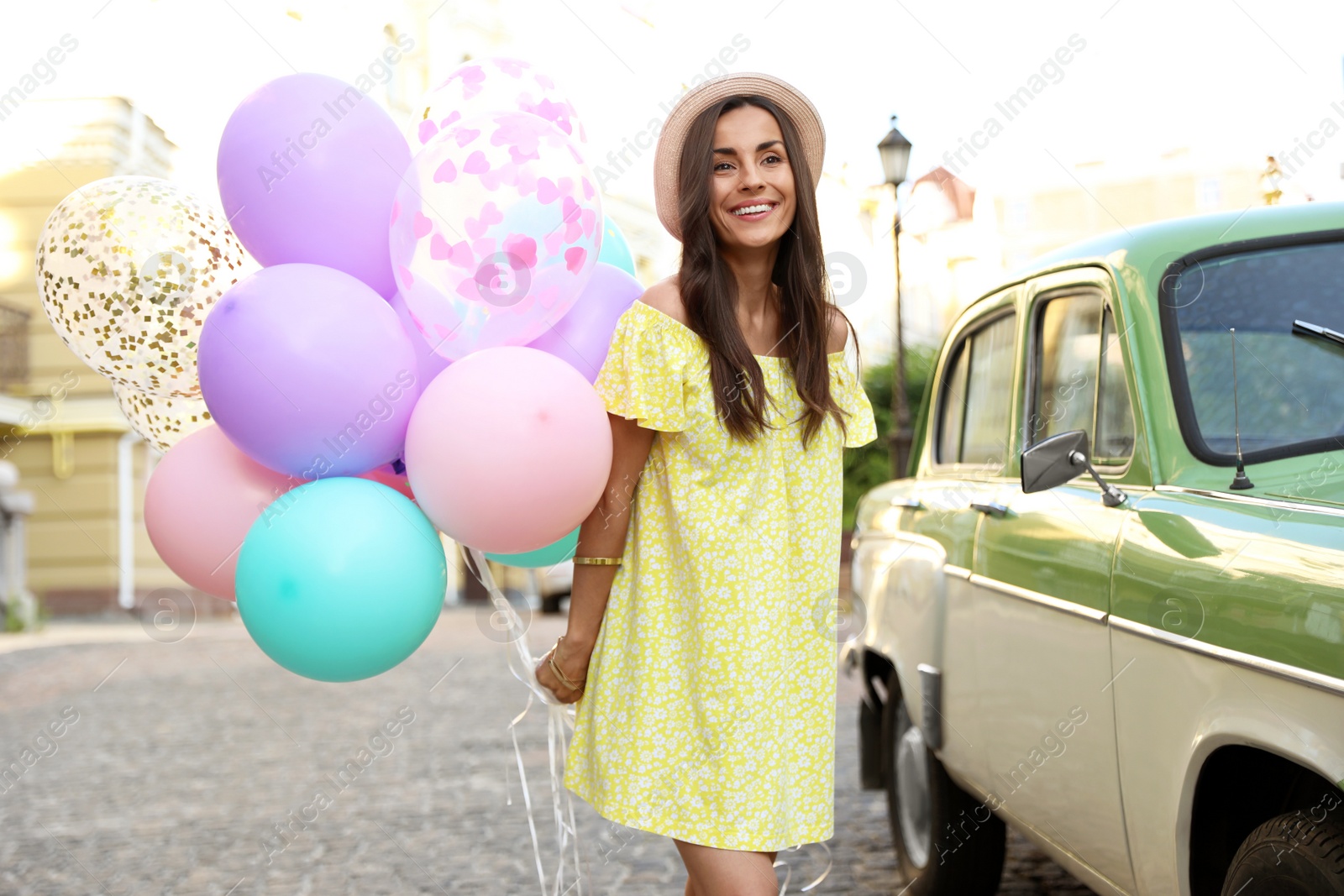 Photo of Beautiful young woman with color balloons on city street