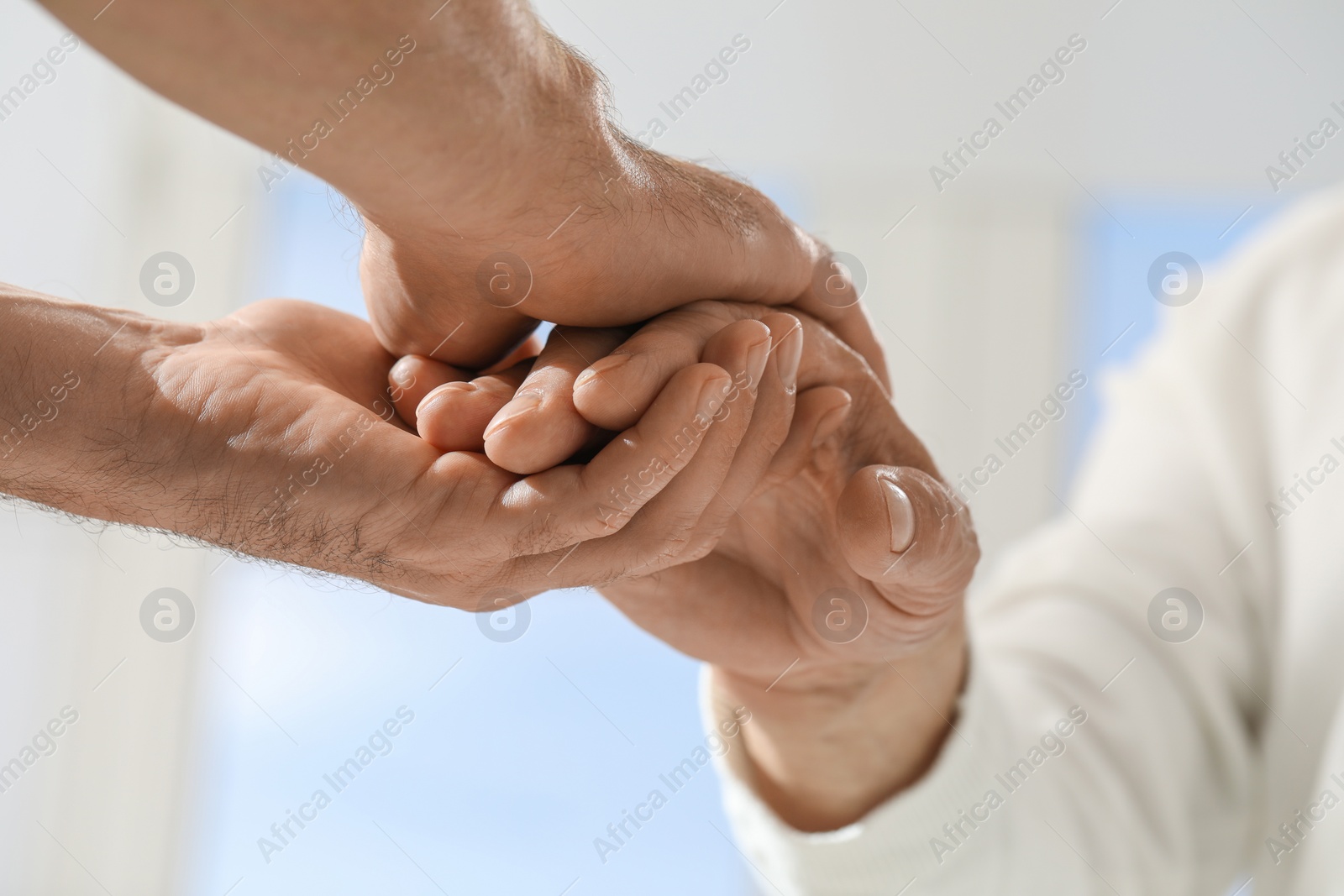 Photo of Trust and support. Men joining hands indoors, closeup