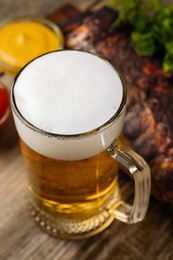 Mug with tasty beer on wooden table