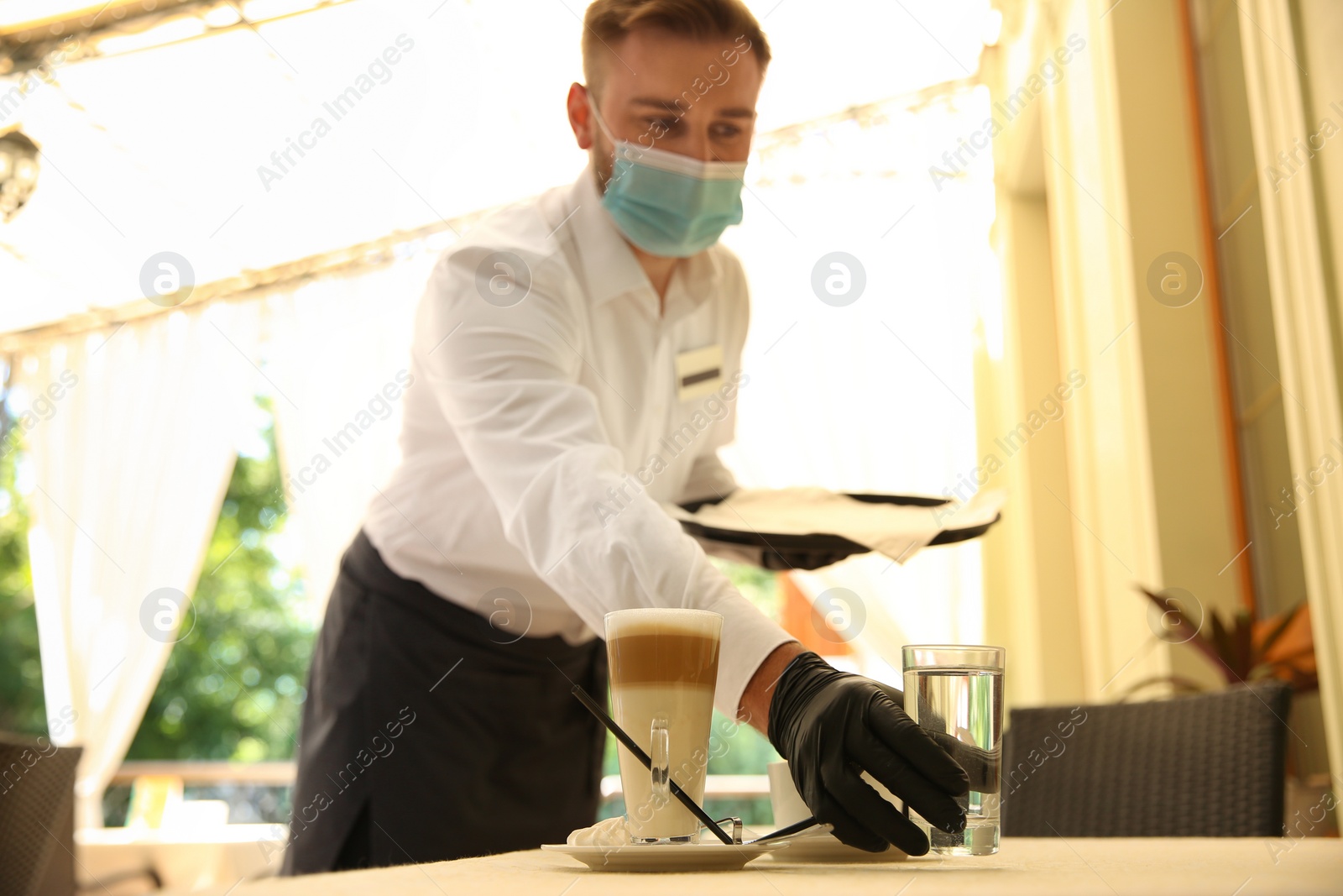 Photo of Waiter serving beverages in restaurant. Catering during coronavirus quarantine