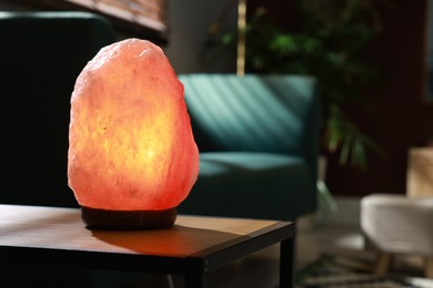 Photo of Himalayan salt lamp on wooden table indoors, space for text